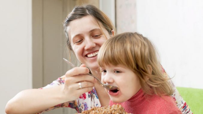 Mother with chil eats buckwheat porridge