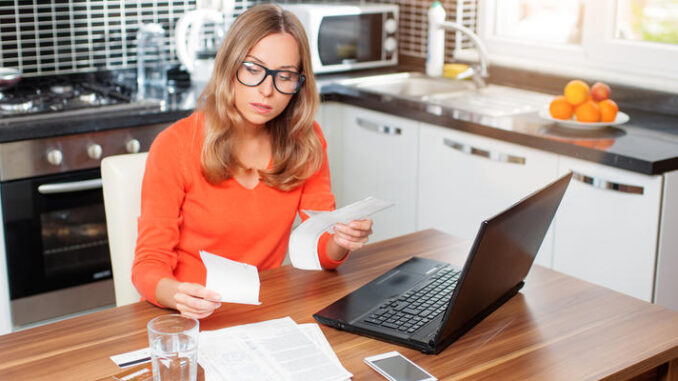 young woman using a laptop computer sitting at her kitchen hold