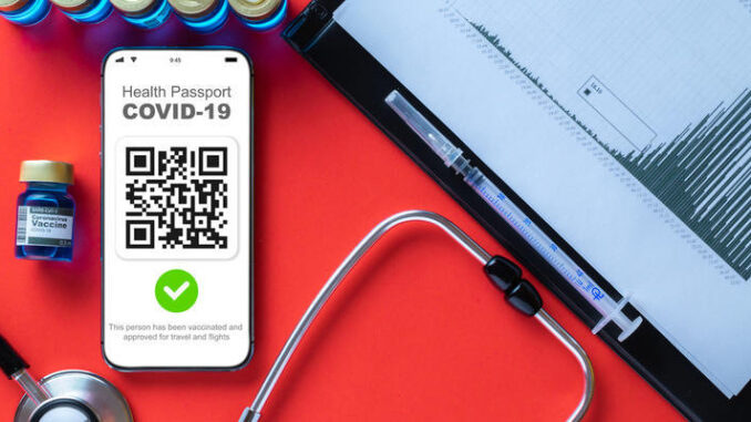 Covid certificate. Medical equipment with Coronavirus vaccination passport or vaccine certificate on phone screen, healthcare charts, syringe and doctor stethoscope on hospital red background.