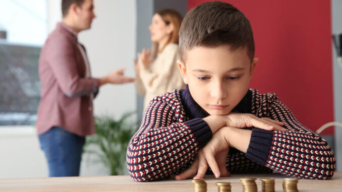 Sad little boy with coins and his quarreling parents at home. Concept of child support